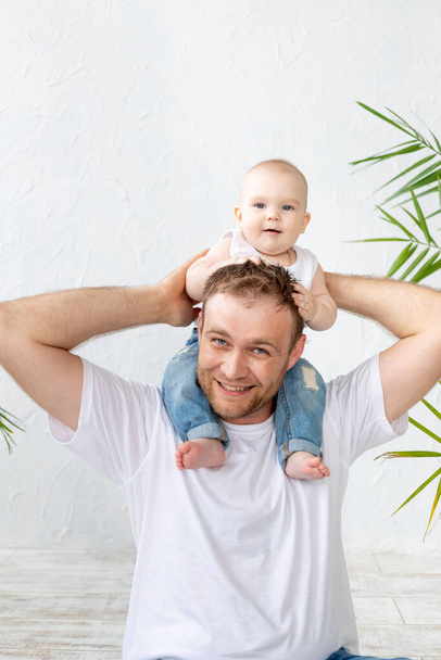 μπαμπάς με το μωρό γιο γύρω από το λαιμό του να διασκεδάζει σε λευκό φόντο, ευτυχισμένη πατρότητα και οικογένεια, ημέρα του πατέρα - Φωτογραφία, εικόνα