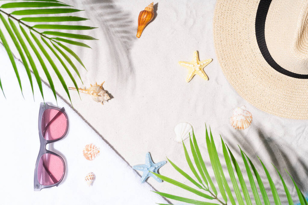 Deniz kabuğu, güneş gözlüğü ve kumdaki şapkayla yaz tatili. - Fotoğraf, Görsel