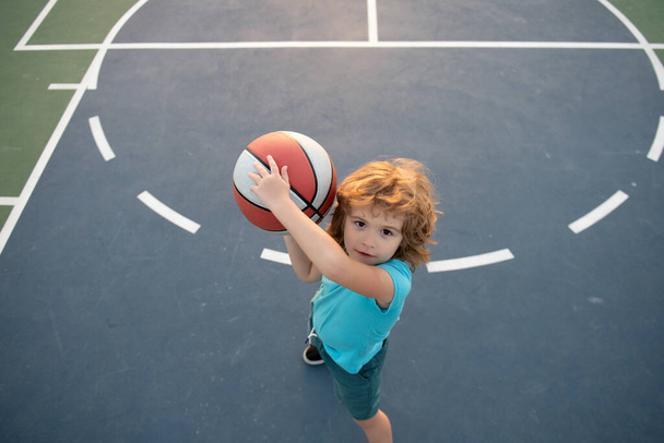 Cute little boy holding a basket ball trying make a score. Sport for kids, Top view. - Фото, зображення