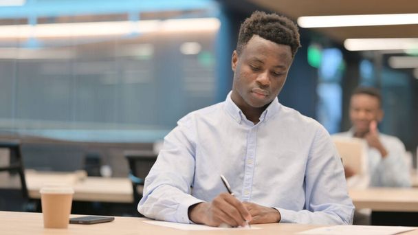 Homme d'affaires africain pensif écrivant sur papier, pensant  - Photo, image