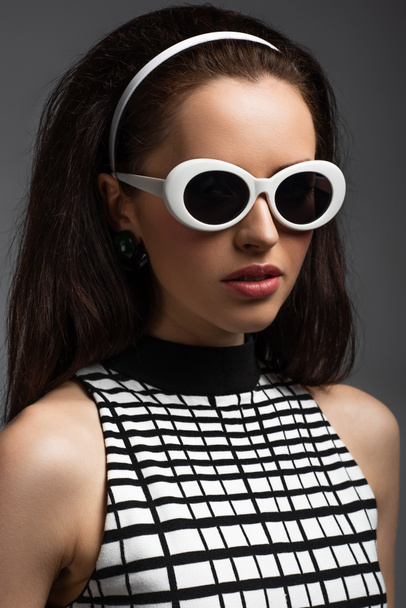 young woman in headband and stylish sunglasses isolated on grey - Photo, Image