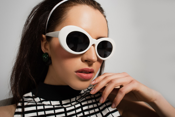 young woman in white retro sunglasses isolated on grey - Foto, afbeelding