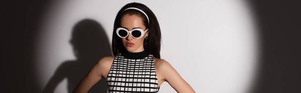 освітлення на стильній моделі в сонцезахисних окулярах позує на сірому, банер
 - Фото, зображення