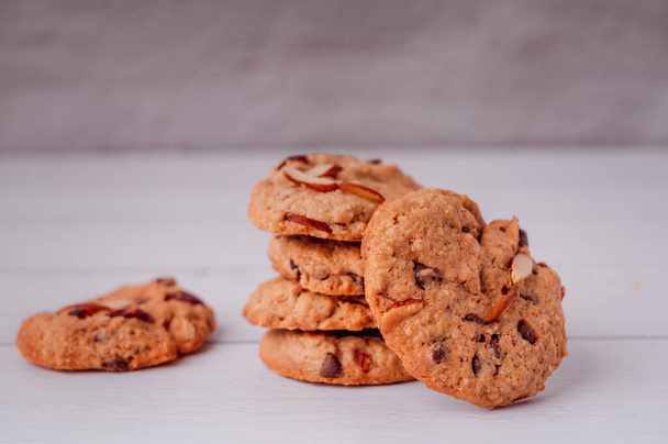 Piles of delicious chocolate chip cookies on a white plate with a milk bottle. Pastry utensils with white linen napkins on a wooden table. Delicious on a white plate with a bottle of milk. - Foto, afbeelding