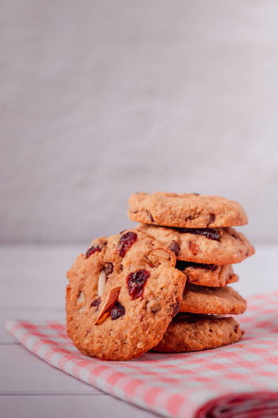 Piles of delicious chocolate chip cookies on a white plate with a milk bottle. Pastry utensils with white linen napkins on a wooden table. Delicious on a white plate with a bottle of milk. - Foto, imagen