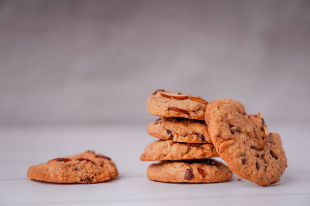 Piles of delicious chocolate chip cookies on a white plate with a milk bottle. Pastry utensils with white linen napkins on a wooden table. Delicious on a white plate with a bottle of milk. - Φωτογραφία, εικόνα