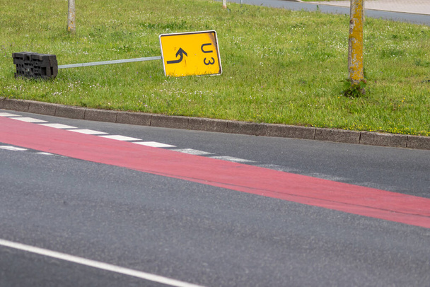 Gelbes Verkehrszeichen zur Umleitung auf innerstädtischen Straßen zwingt das Navigationssystem zur Berechnung einer neuen Route für die korrekte Routenführung zum Ziel auf deutschen Straßen, die nach starkem Sturm im Gras liegen - Foto, Bild