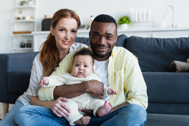 joyeux couple interracial avec bébé enfant souriant à la caméra - Photo, image
