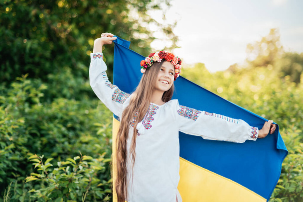 Ukraine's Independence Flag Day. Constitution day. Ukrainian child girl in embroidered shirt vyshyvanka with yellow and blue flag of Ukraine in field. flag symbols of Ukraine. Kyiv, Kiev day - Фото, зображення
