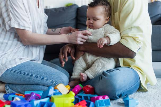 interracial parents playing with infant child near colorful building blocks - Fotografie, Obrázek
