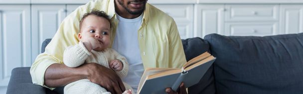 アフリカ系アメリカ人の男性が幼い娘バナーに本を読んで - 写真・画像