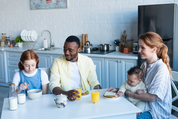 happy interracial family having breakfast in kitchen - Fotó, kép
