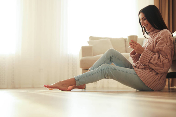 Woman sitting on warm floor in living room. Heating system - Foto, Bild