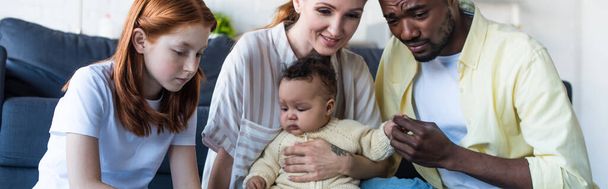 uomo afroamericano toccando mano della figlia neonata vicino alla famiglia, striscione - Foto, immagini