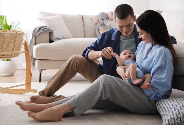Happy family with cute baby near sofa at home - Foto, afbeelding