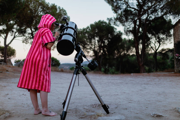 Frau betrachtet den Mond durch ein Teleskop - Foto, Bild