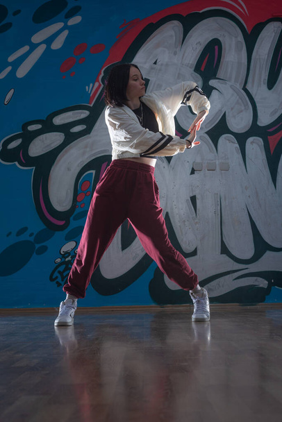 junge athletische schlanke Tänzerin, die auf dunklem Hintergrund auftritt und springt, Fitness- und Vitalitätskonzept - Foto, Bild