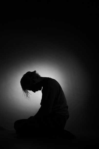 Σιλουέτα καταθλιπτικού και θλιμμένου αγοριού με το κεφάλι κάτω, μαύρο και άσπρο - Φωτογραφία, εικόνα
