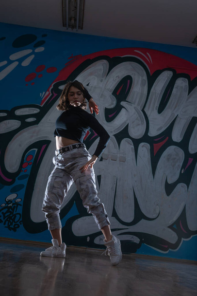 Silhouette of young woman hiphop dancer (breakdancer)dancing on graffiti studio background. Contrast colors. - Foto, Imagem