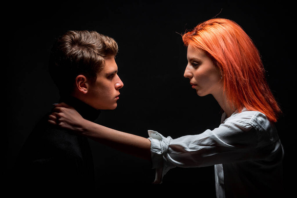 Молодий хлопець і дівчина позують пліч-о-пліч на темному тлі
 - Фото, зображення
