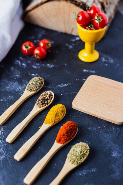 The wooden spoons with spices, paprika, basilic, pepper, thyme with cherry tomatoes - Valokuva, kuva