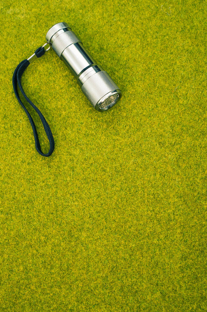 A top view shot of a flashlight on a green grass surface - 写真・画像