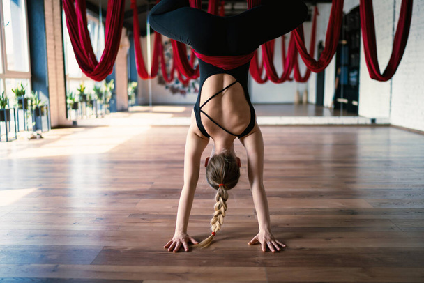 A focus of aerial yoga swings on background of a flexible female practicing a fly yoga pose - Foto, imagen