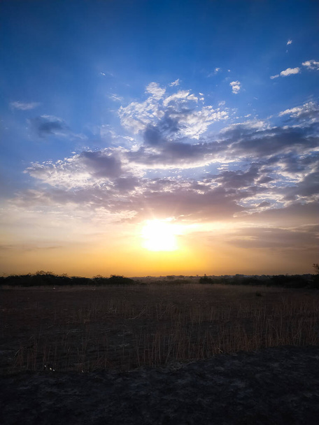 The golden sun rising in the cloudy sky on the field - Fotó, kép