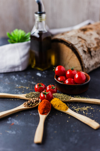 The wooden spoons with spices, paprika, basilic, pepper, thyme with cherry tomatoes - Foto, Imagen