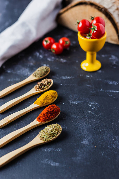 The wooden spoons with spices, paprika, basilic, pepper, thyme with cherry tomatoes - Foto, immagini