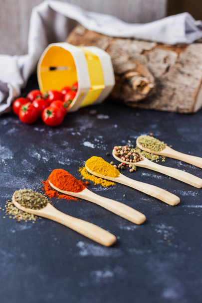 The wooden spoons with spices, paprika, basilic, pepper, thyme with cherry tomatoes - 写真・画像