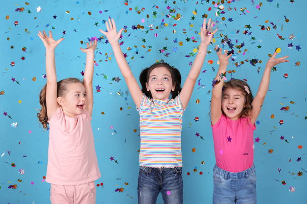 Schattige kleine kinderen en vallende confetti op lichtblauwe achtergrond - Foto, afbeelding