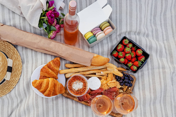 Picnic with strawberries, croissants and appetizers on the board and rose wine - Foto, imagen