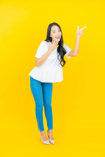 Portrait beautiful young asian woman smile with action on yellow color background - Foto, Imagem