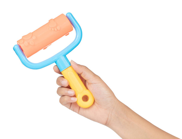 Hand hält Kunststoff-Werkzeugwalzenbürste von Strandspielzeug isoliert auf weißem Hintergrund - Foto, Bild