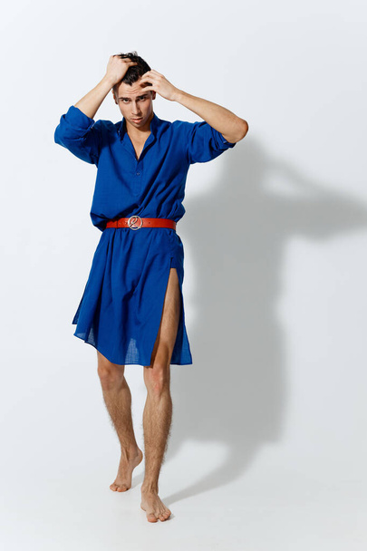 handsome gay man on a light background in full growth and a red belt model blue dress - Photo, Image