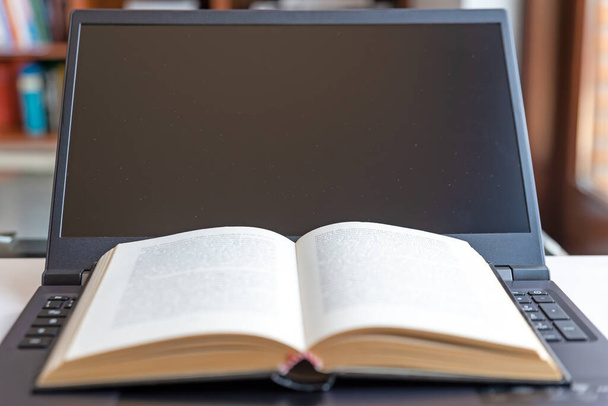 Notebookcomputer, met boeken geplaatst op het zwarte toetsenbord. E-learning en lessen op afstand. - Foto, afbeelding
