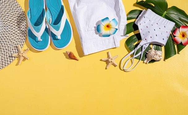 Conceito de verão e férias. acessórios de verão com roupas, sapatos, folhas tropicais e flores, flat lay no fundo amarelo - Foto, Imagem