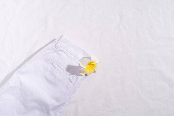 Summer and vacation concept. White summer jeans with plumeria flower on white background. Mock up design - Zdjęcie, obraz