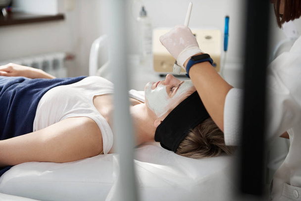 Vista de alto ángulo de esteticista aplicando una máscara algínica en una hermosa cara de mujer en la clínica de spa. Concepto de cuidado de la piel profesional - Foto, imagen