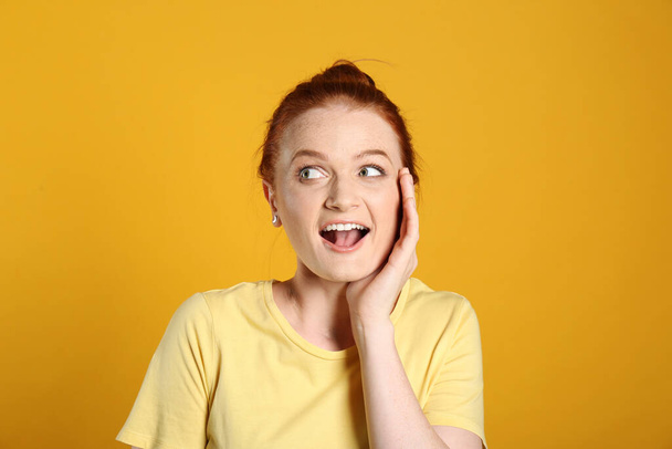Portrait of emotional red haired woman on yellow background - Фото, изображение