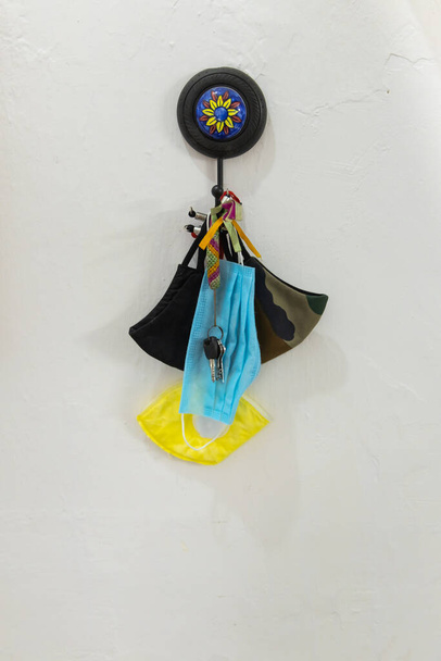 Gesichtsmasken verschiedener Art hängen mit einem Schlüsselbund an der Wand - Foto, Bild