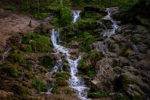Prachtige berg regenwoud waterval met snel stromend water en rotsen, lange blootstelling. Natuurlijke seizoensgebonden reizen outdoor achtergrond met zon shihing - Foto, afbeelding