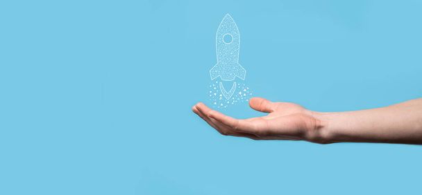 Male hand holding digital transparent rocket icon.Startup business concept. Rocket is launching and soar flying.Concept of business idea - Photo, Image