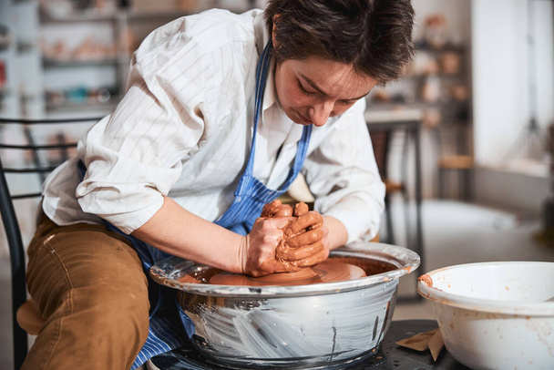 Kind craftsperson processing clay on special wheel - 写真・画像