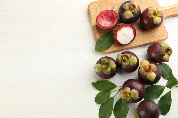 Fresh ripe mangosteen fruits on white wooden table, flat lay. Space for text - Photo, Image