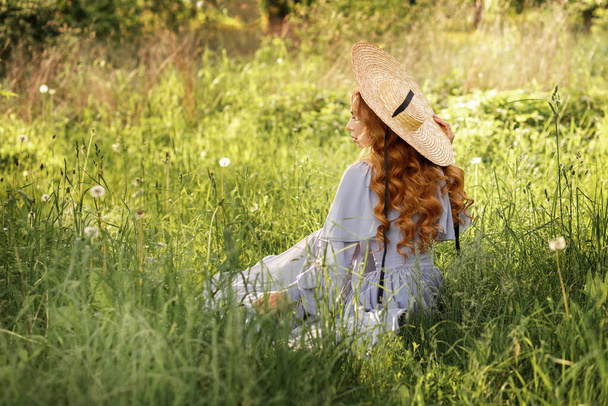 Κορίτσι με καπέλο κάθεται πίσω στον κήπο το καλοκαίρι - Φωτογραφία, εικόνα