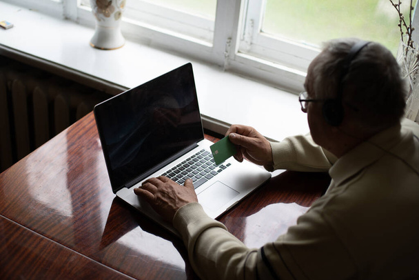 Elderly man with glasses using laptop at home - Foto, afbeelding