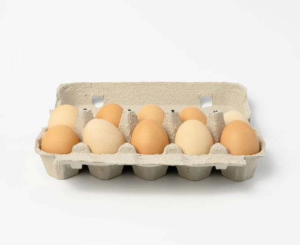 Kağıt ambalajlı taze kahverengi yumurtalar beyaz arka planda izole edilmiş. - Fotoğraf, Görsel