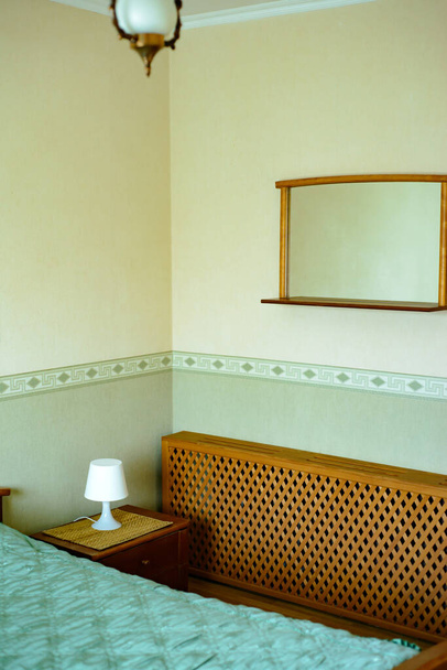 Sypialnia zielona z łóżkiem, szafka nocna z lampką nocną i lustrem w rustykalnym domu - Zdjęcie, obraz